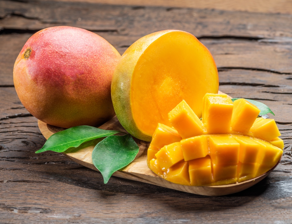 Mango fruits and mango slices on the old wooden table.