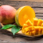 Mango fruits and mango slices on the old wooden table.