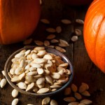 pile of pumpkin seeds next to pumpkins