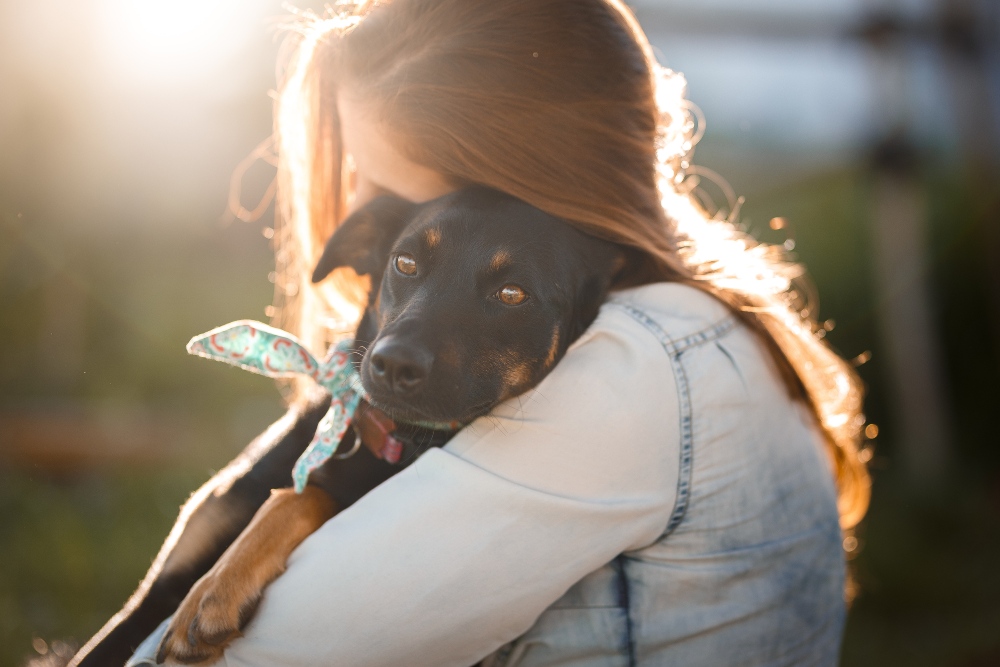 woman hugging black rescue dog